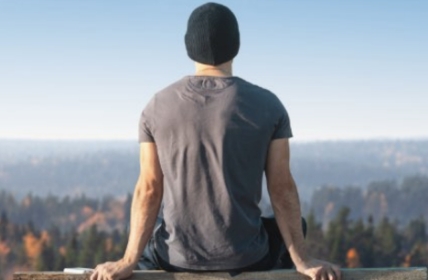 Mann sitzt auf einer Bank und schaut in die Ferne